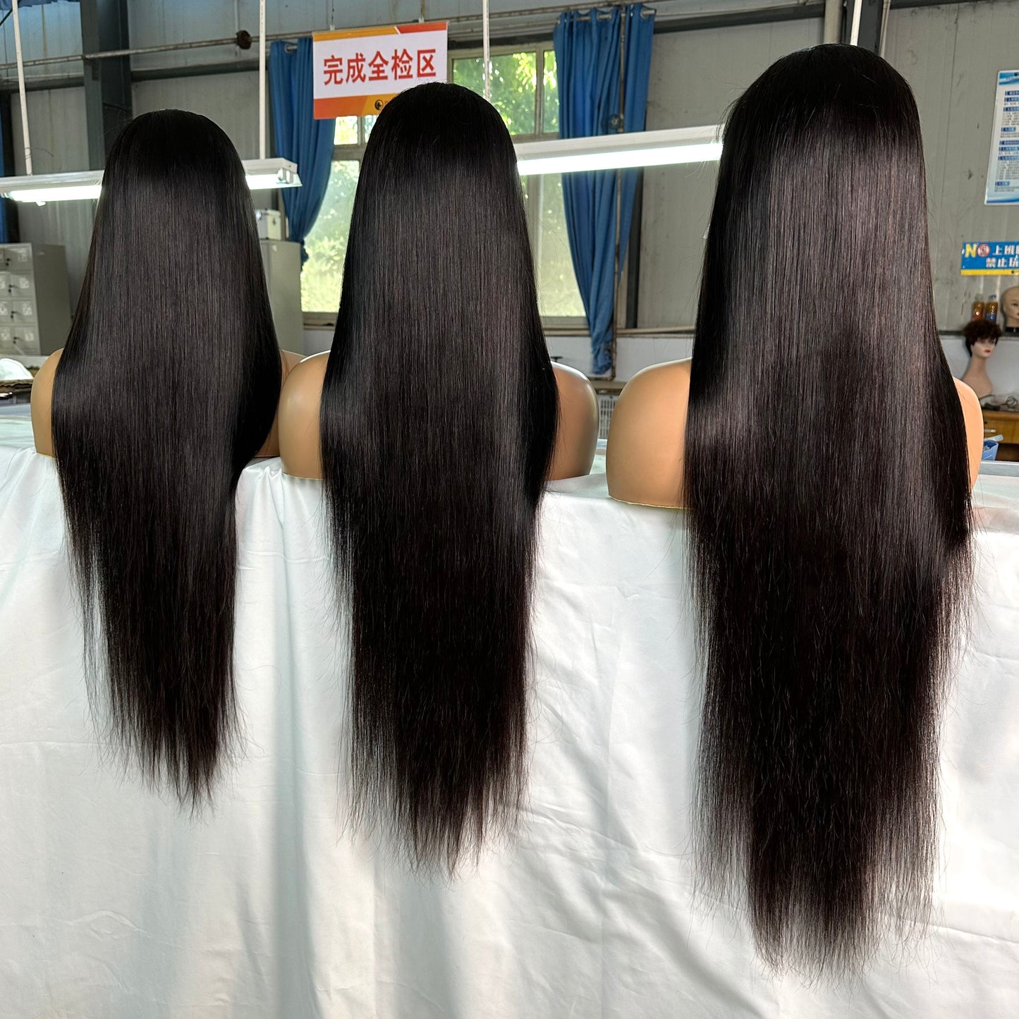 Three mannequin heads with long, straight, black hair in a hair manufacturing or inspection room