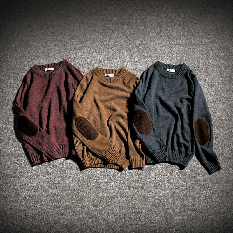 Three cozy knit sweaters in burgundy, brown, and dark gray with elbow patches laid on carpet