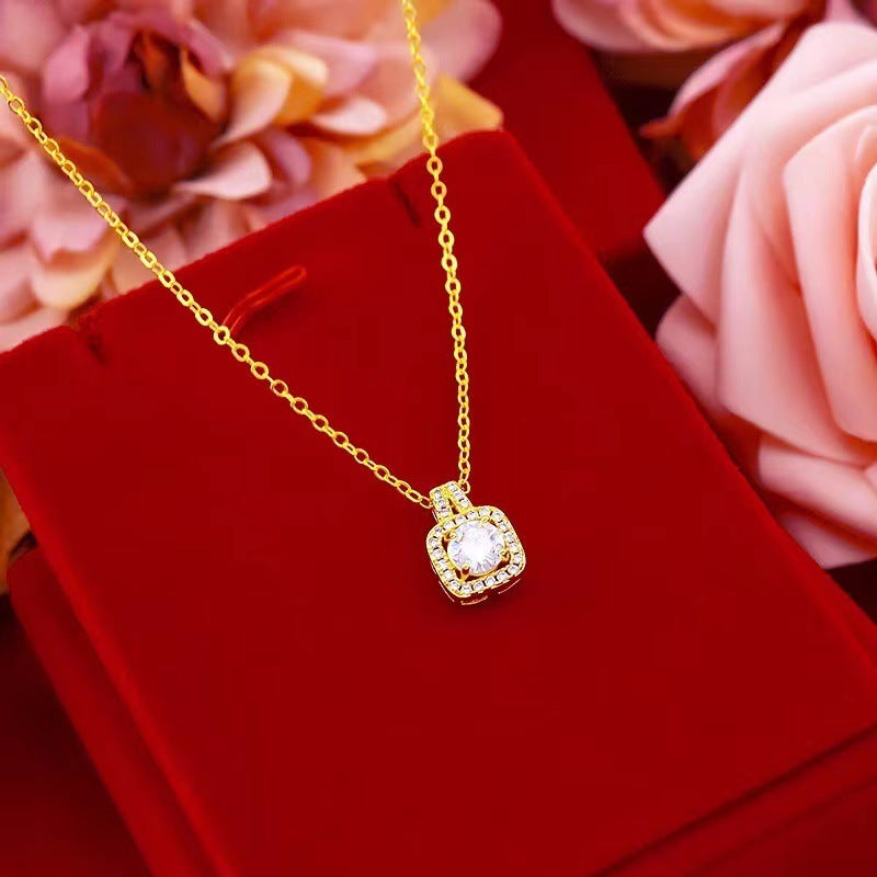 Gold necklace with square diamond pendant on red velvet box, surrounded by pink roses