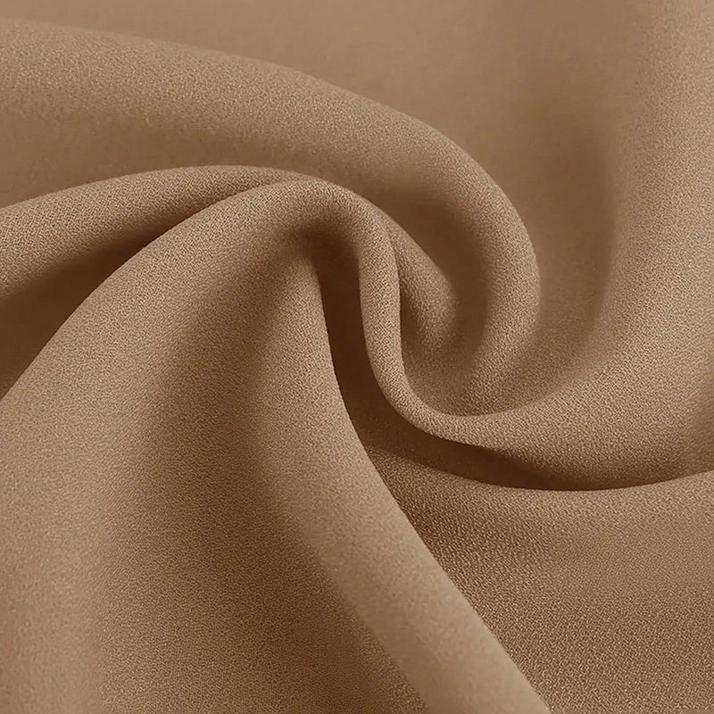 Close-up of smooth tan fabric with fine texture, softly folded in a swirl pattern