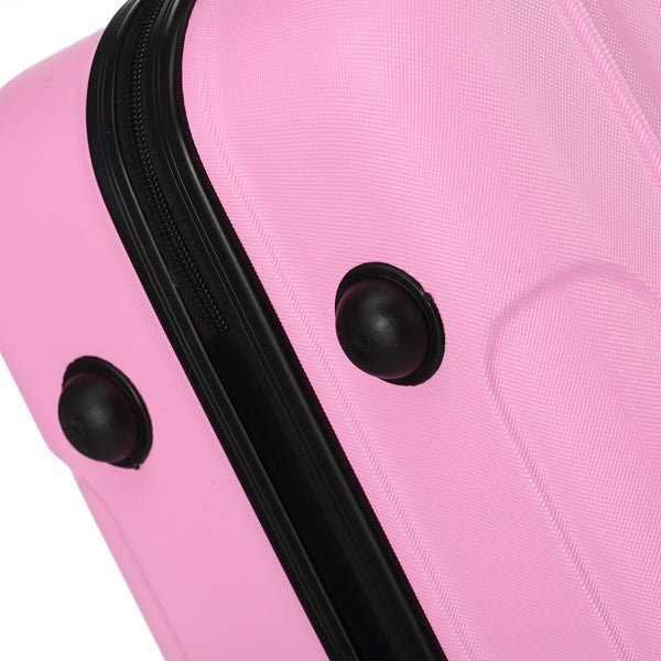 Close-up of pink hard-shell suitcase corner with black zipper and protective bumpers