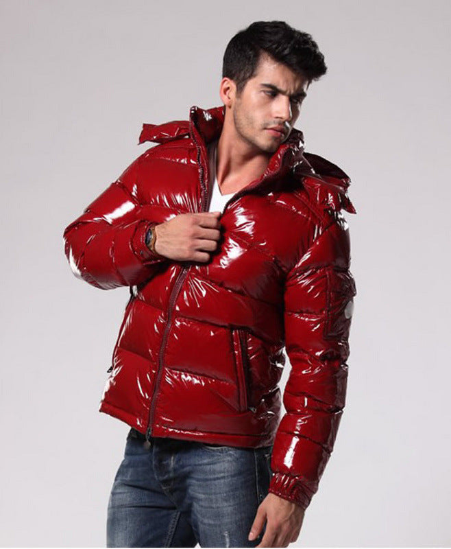 Man wearing shiny red puffer jacket and blue jeans posing against gray background