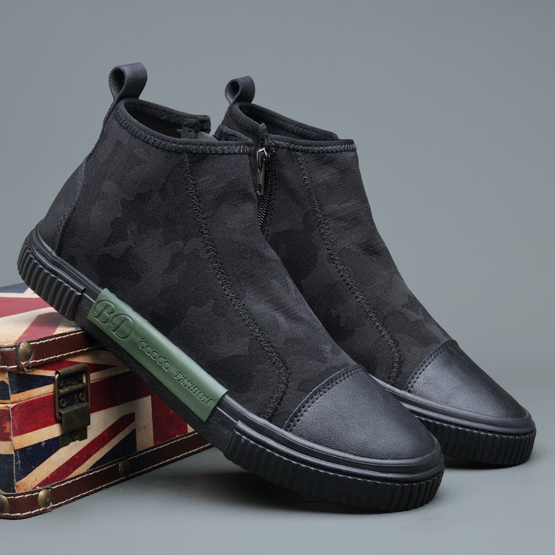 Black high-top sneakers with subtle camouflage pattern and side zipper, displayed on UK flag suitcase