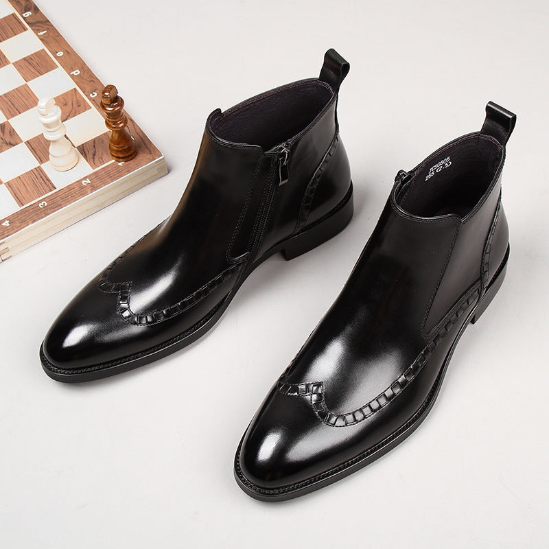 Pair of polished black leather ankle boots with zippers and woven details on white background next to a chessboard