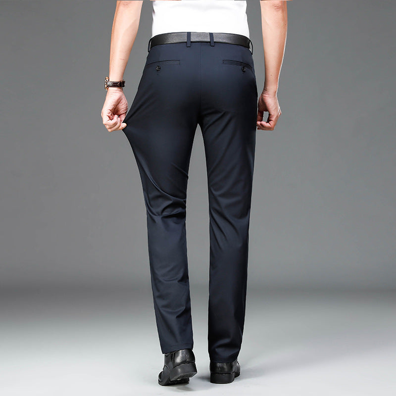 Man wearing slim fit navy blue dress pants with black belt and black shoes on gray background