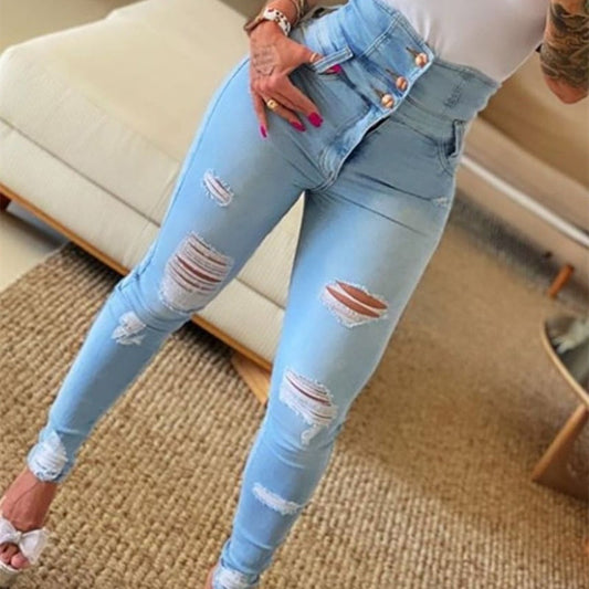 Woman wearing light blue high-waisted ripped skinny jeans and white top in a modern living room