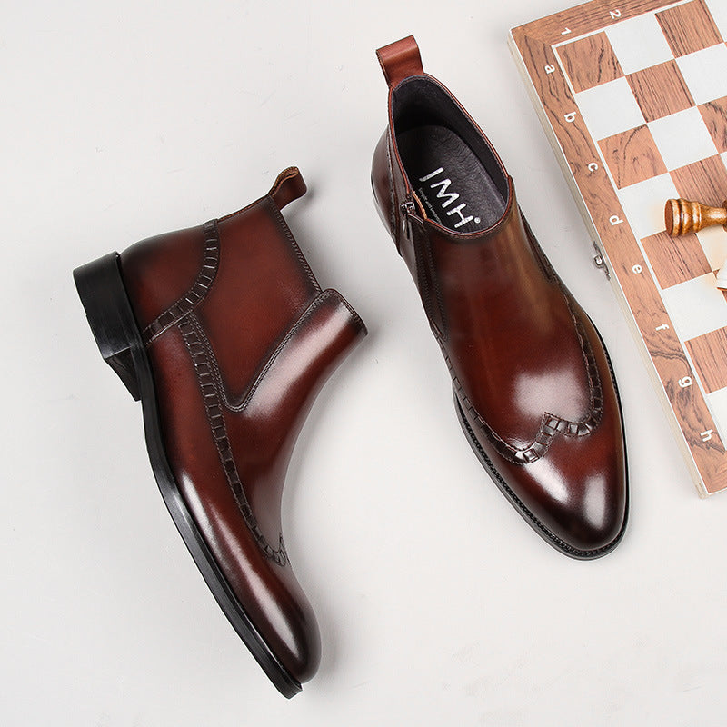 Pair of polished brown leather Chelsea boots with decorative stitching beside a wooden chessboard