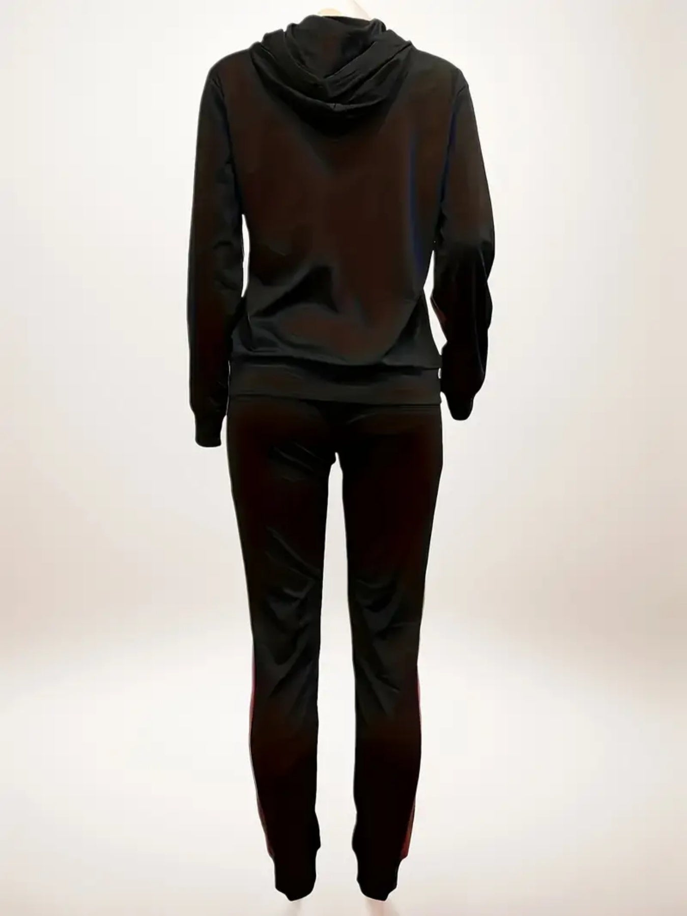 Back view of person wearing black hoodie and matching black pants against plain background