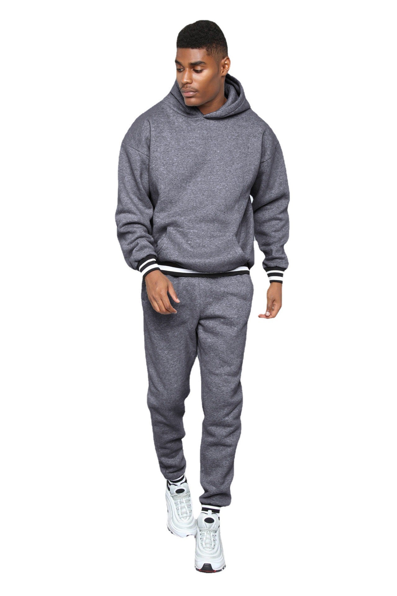 Man wearing gray hoodie and sweatpants with white sneakers on white background