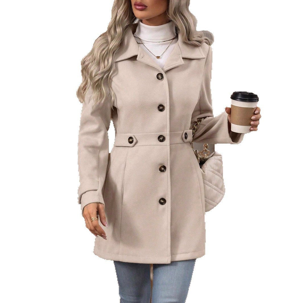 Woman wearing beige buttoned winter coat with belt, holding coffee cup and quilted handbag