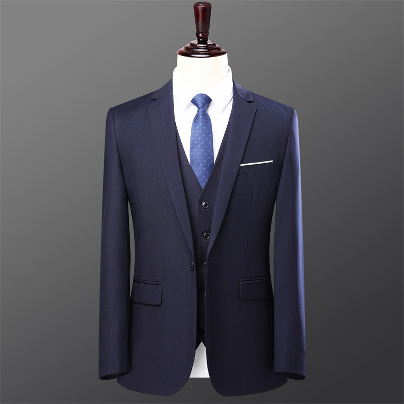 Navy blue men's three-piece suit with white shirt and blue patterned tie on mannequin