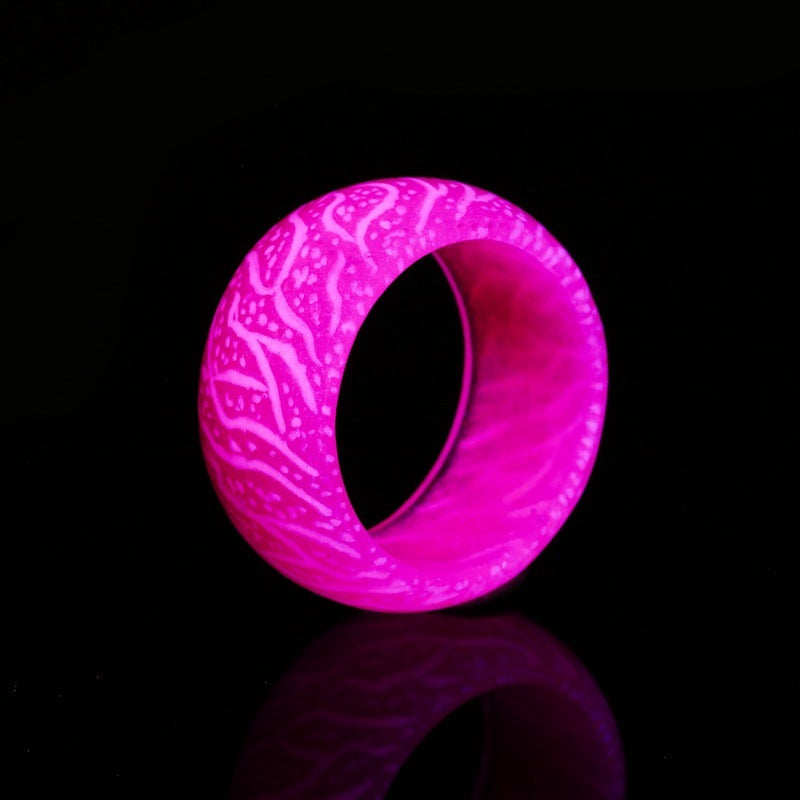 Glowing pink silicone ring with intricate white pattern on black background