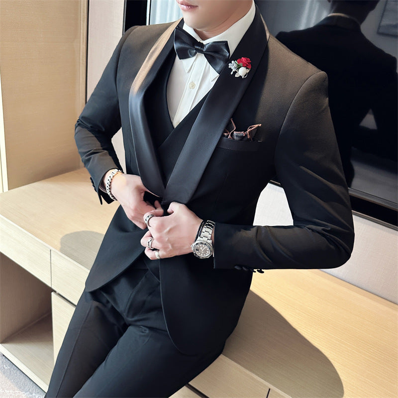 Man wearing black tuxedo with satin lapels, white shirt, black bow tie, and red flower lapel pin