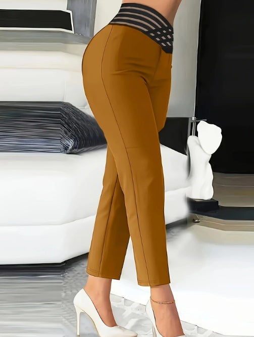 Woman wearing mustard tapered pants with striped waistband and white high heels in modern living room