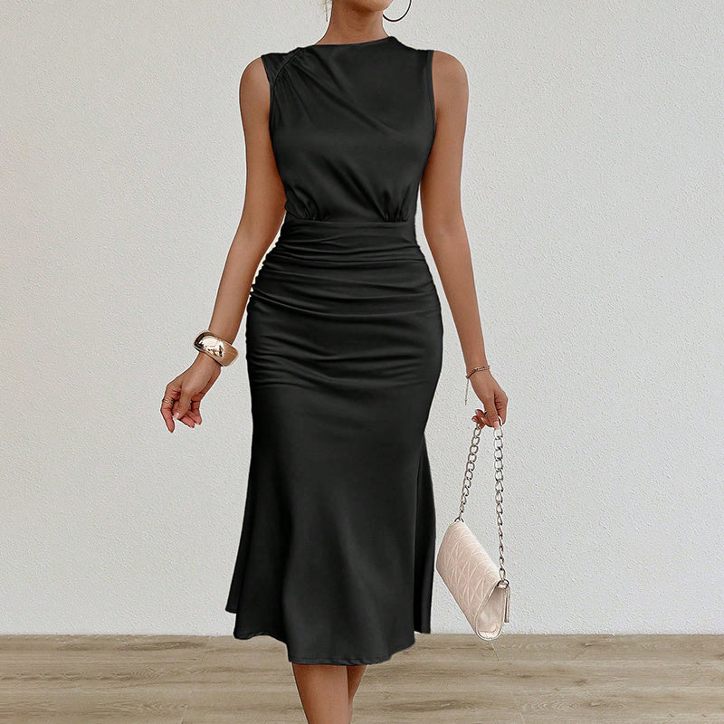 woman wearing a sleeveless black ruched midi dress holding a beige quilted chain purse
