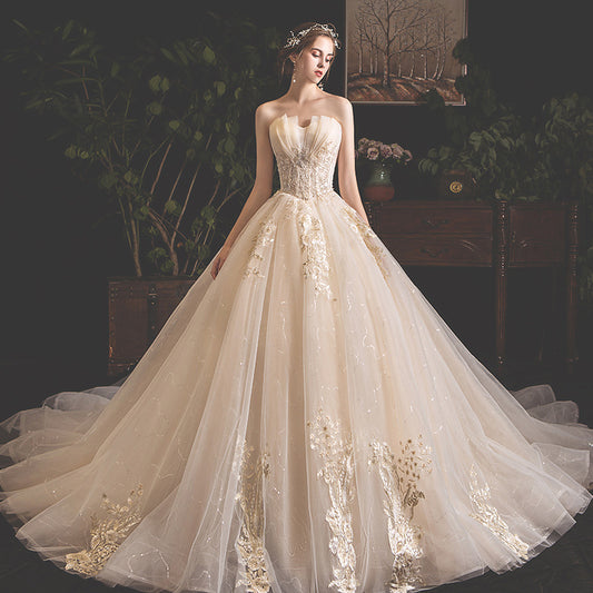 Elegant strapless ivory wedding dress with intricate gold floral embroidery, full tulle skirt, and tiara