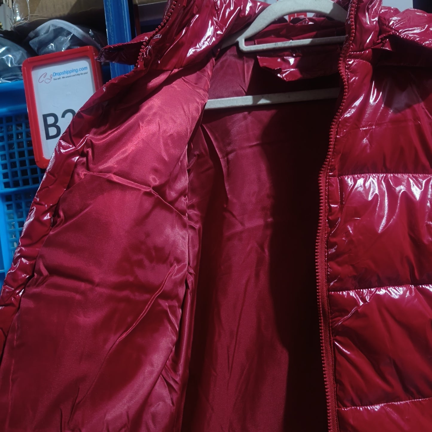 Red shiny puffer jacket hanging open on a white hanger showing silky inner lining and zipper