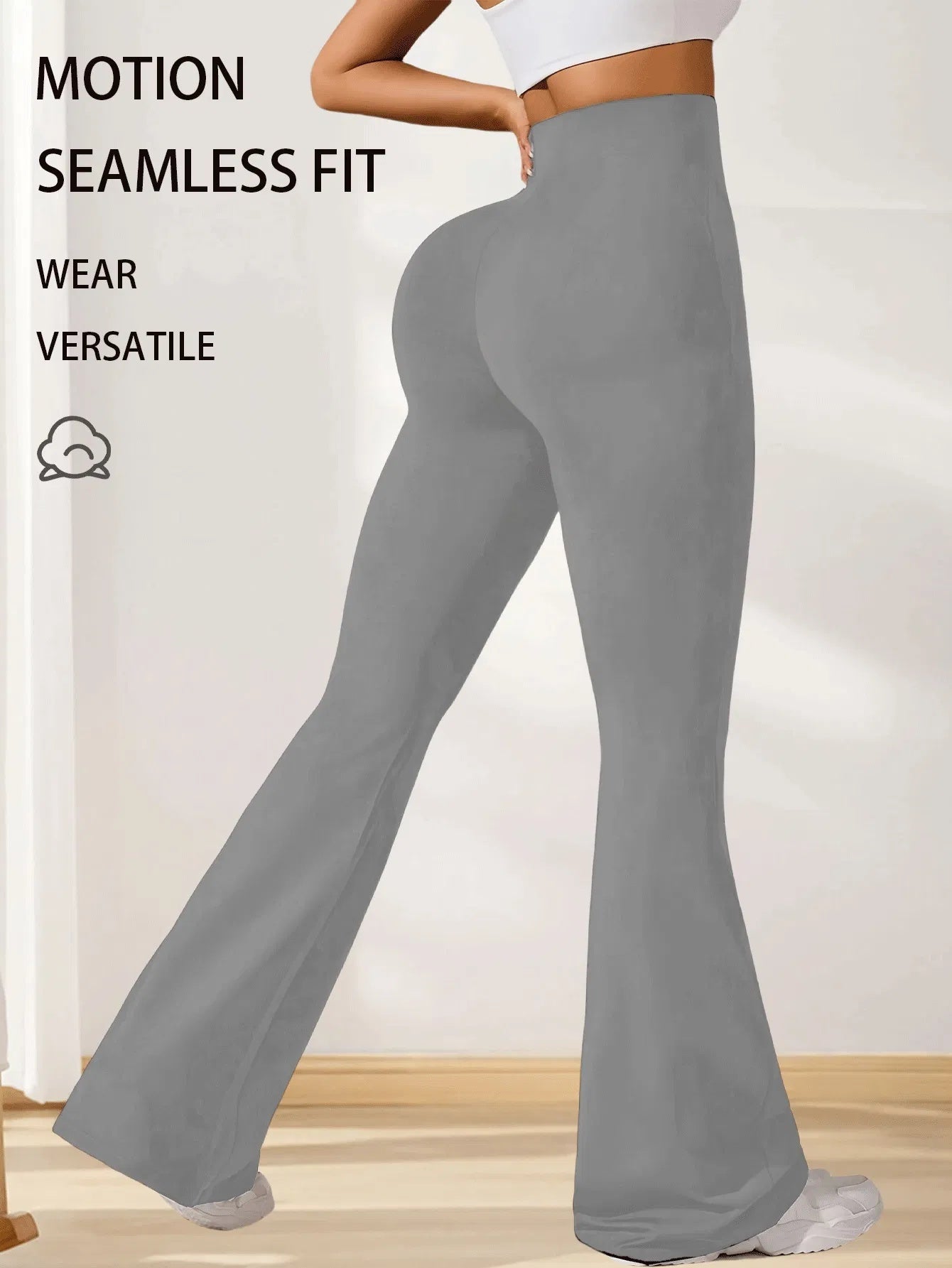 Woman wearing gray seamless fit flared pants paired with white crop top and sneakers indoors