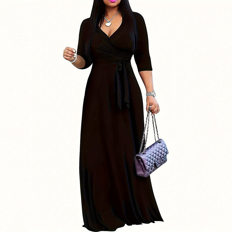 Woman in a black wrap maxi dress holding a quilted purple handbag with chain straps