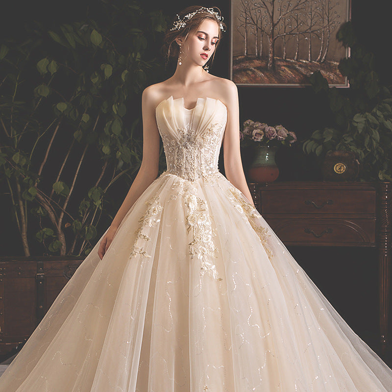 Bride in elegant strapless ivory wedding gown with floral embroidery and full skirt indoors