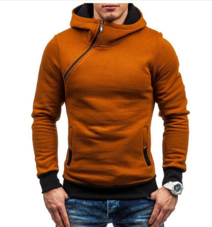 Man wearing a stylish burnt orange hoodie with black cuffs and zipper detail, paired with blue jeans