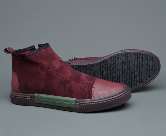 Stylish men's maroon suede sneakers with textured black rubber sole and green side label on gray background