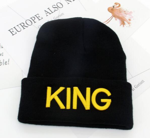 Black knit beanie hat with bright yellow embroidered KING text on cuff, placed on white paper background