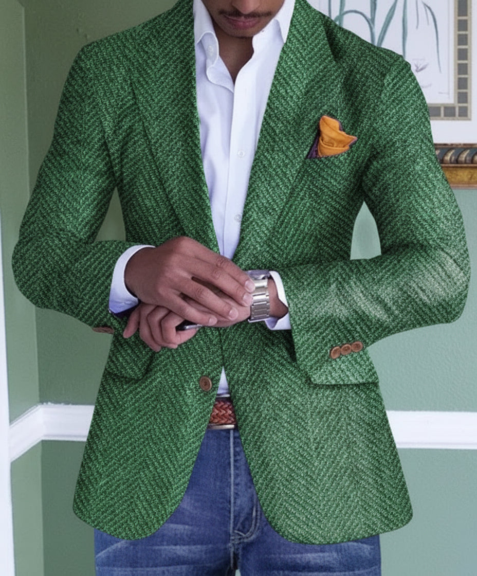 Man in green herringbone blazer adjusting silver watch with white shirt and jeans indoors