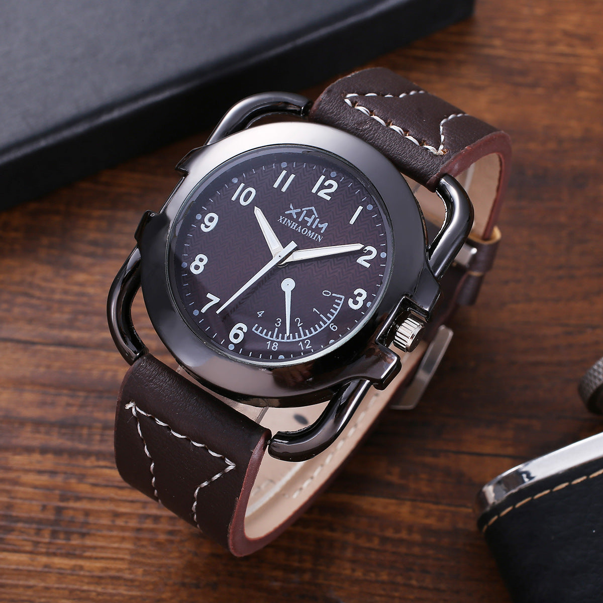 Xinhaomin wristwatch with black round dial and brown leather strap on wooden surface