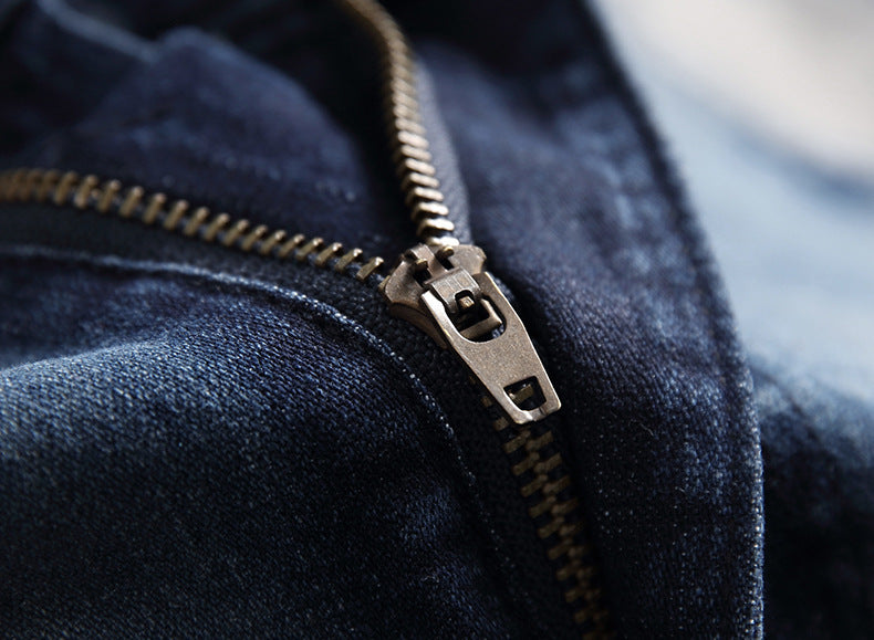 Close-up of a metal zipper on dark blue denim fabric, highlighting texture and stitching