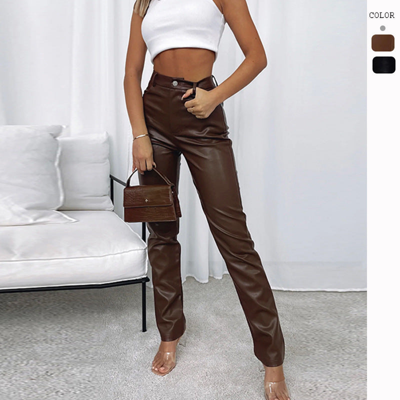 Woman wearing brown faux leather pants with white crop top, clear heels, and holding a brown handbag