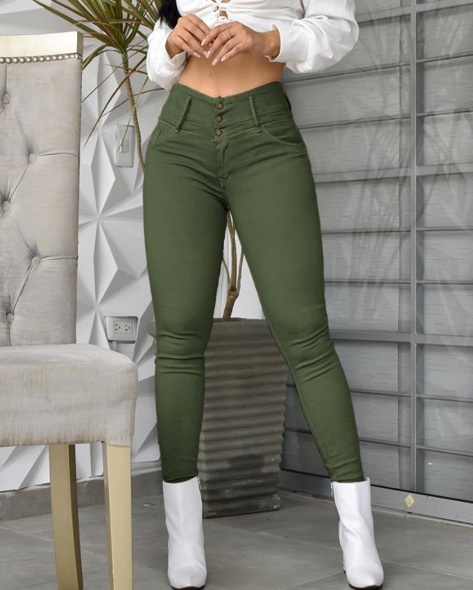 Woman wearing high-waisted olive green skinny jeans and white ankle boots indoors