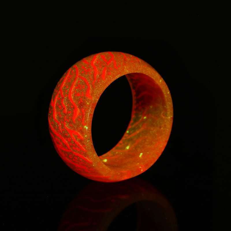 Glowing orange resin ring with intricate red vein patterns on black background