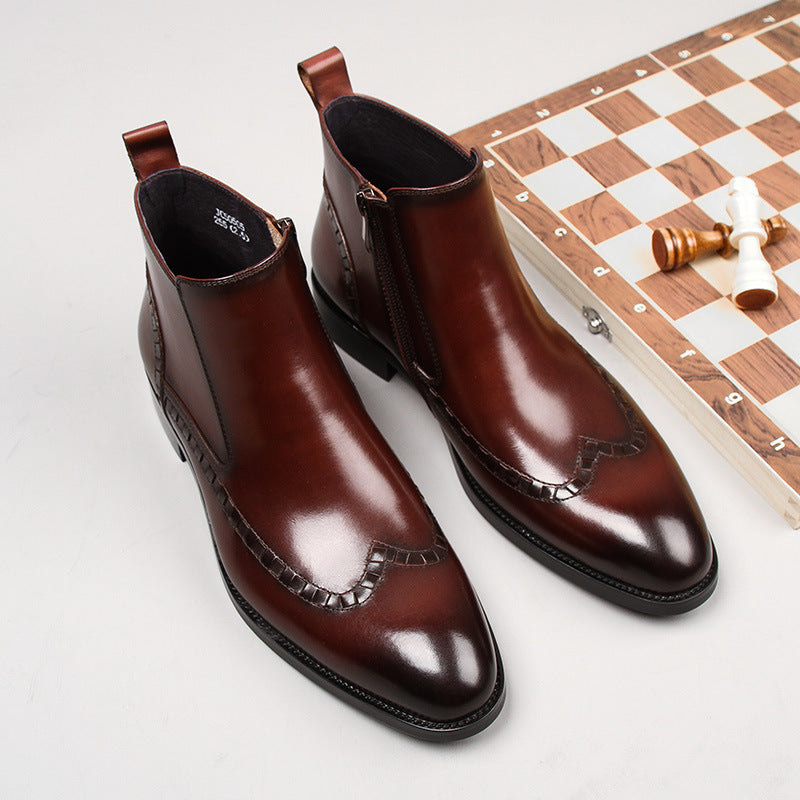 Polished brown leather ankle boots with side zippers beside a wooden chessboard and chess pieces