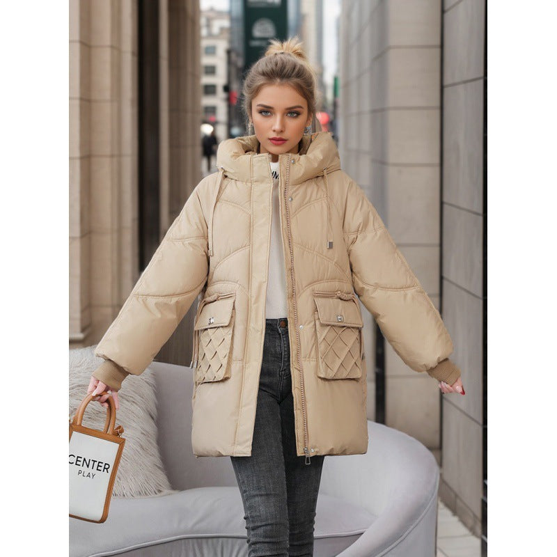 Woman wearing beige padded winter jacket with quilted pockets standing in urban outdoor setting