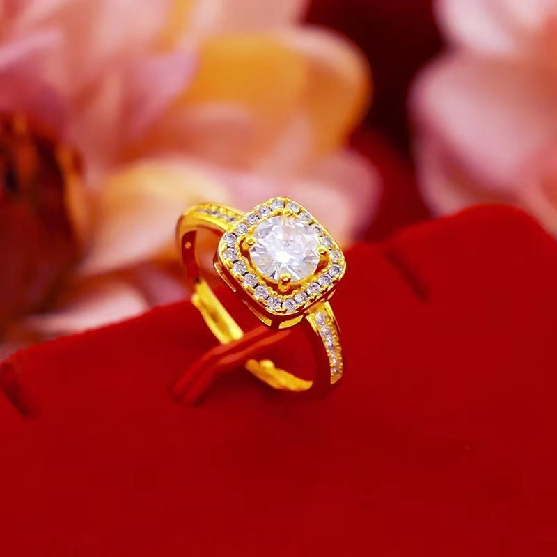 Gold engagement ring with square halo of diamonds and single round center stone on red velvet