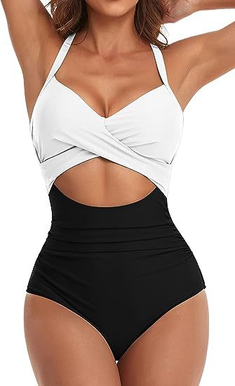 Woman wearing stylish black and white cutout one-piece swimsuit with halter straps