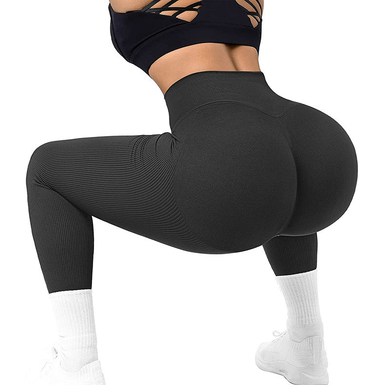 Woman wearing black high-waisted seamless leggings and black sports bra squatting, white sneakers and socks