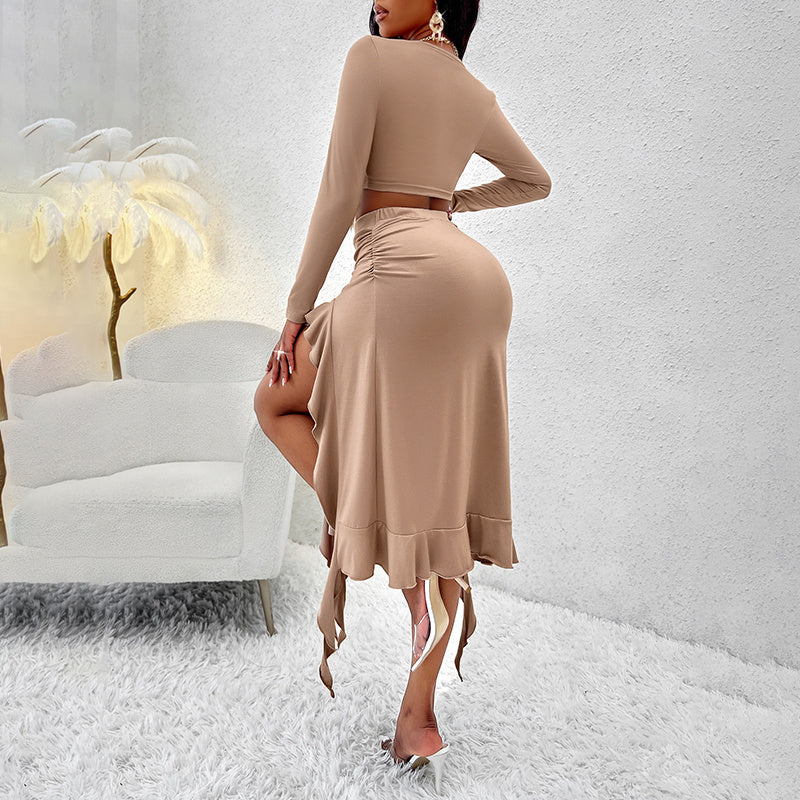 Woman wearing beige two-piece outfit with long-sleeve crop top and asymmetrical skirt in modern white room