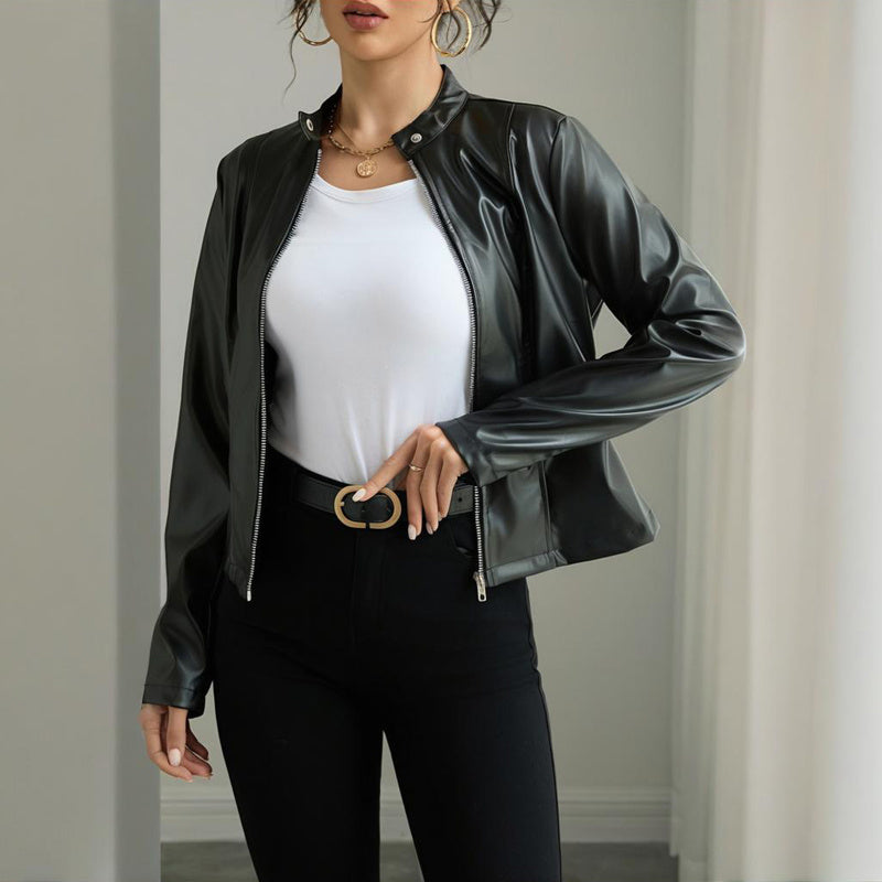 Woman wearing black faux leather jacket, white t-shirt, black pants with gold buckle belt, and gold jewelry