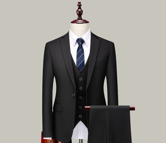 Black three-piece men's suit with white shirt and striped tie on mannequin against gray background