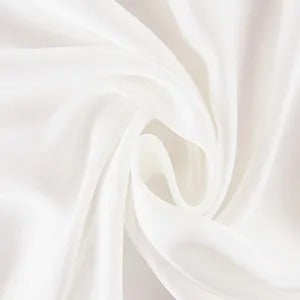 Close-up of smooth, flowing white fabric with soft folds and a swirling pattern