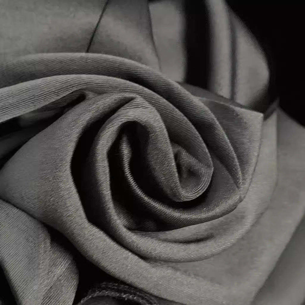 Close-up of soft gray fabric folded in a swirling pattern, highlighting texture and smoothness