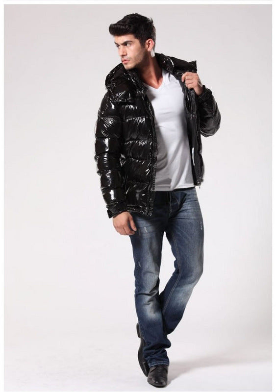Man wearing shiny black puffer jacket, white t-shirt, blue jeans, and black shoes against white background
