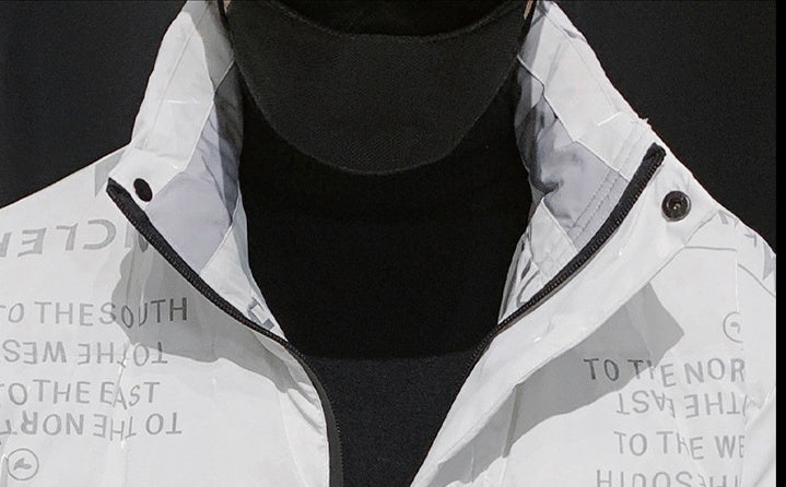 Close-up of a white zip-up jacket with black text and a high collar over a black shirt and black cap