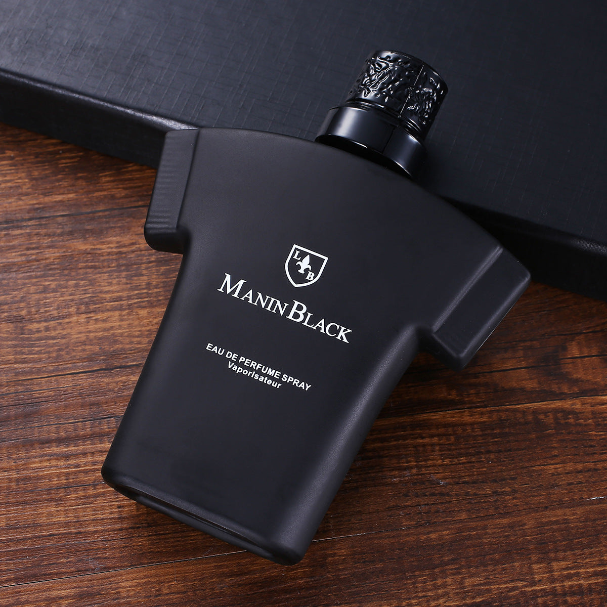 Black matte Manin Black eau de perfume spray bottle on wooden surface with black textured box