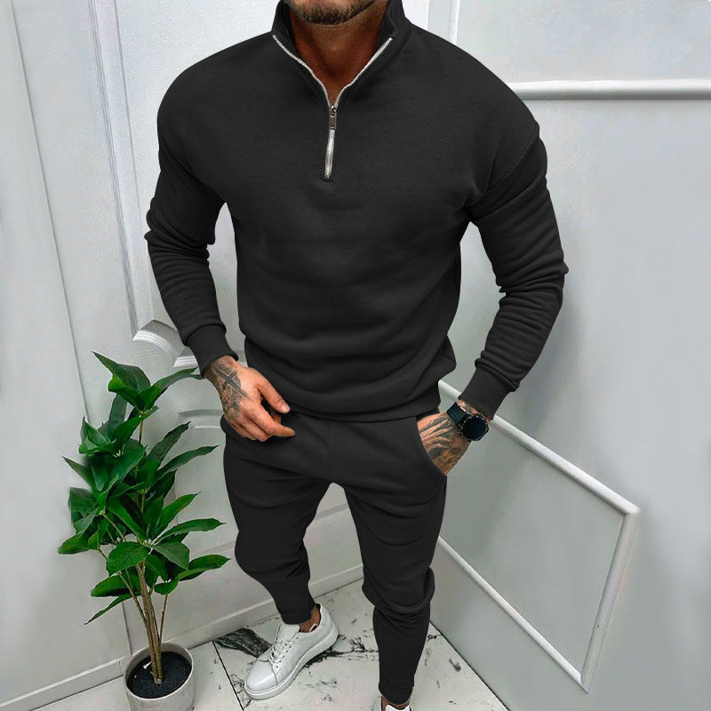 Man wearing stylish black zip-up sweatshirt and matching joggers with white sneakers indoors