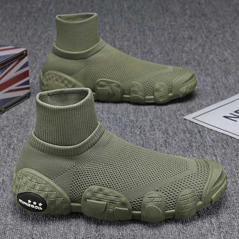 Olive green knitted sock sneakers with textured rubber soles on gray carpet