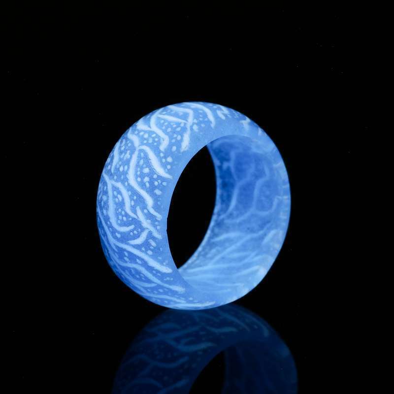 Close-up of a blue translucent ring with white organic patterns on a black reflective surface