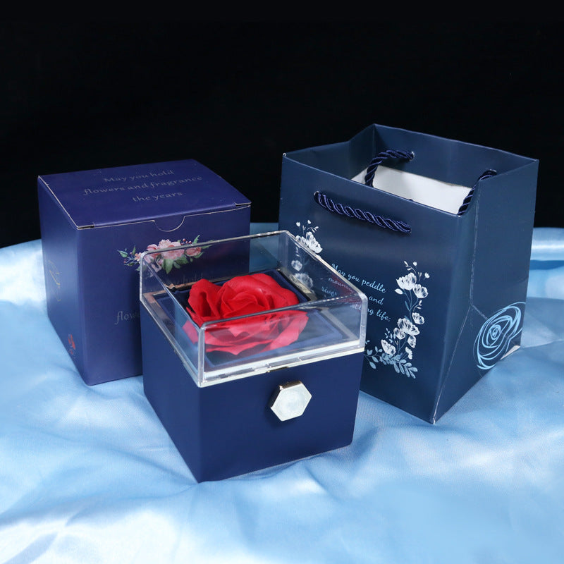 Navy blue gift box with clear lid displaying a red rose, accompanied by matching floral gift bag and box